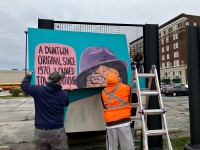 Volunteers for MuncieArts reinstalling a portrait panel in downtown Muncie.